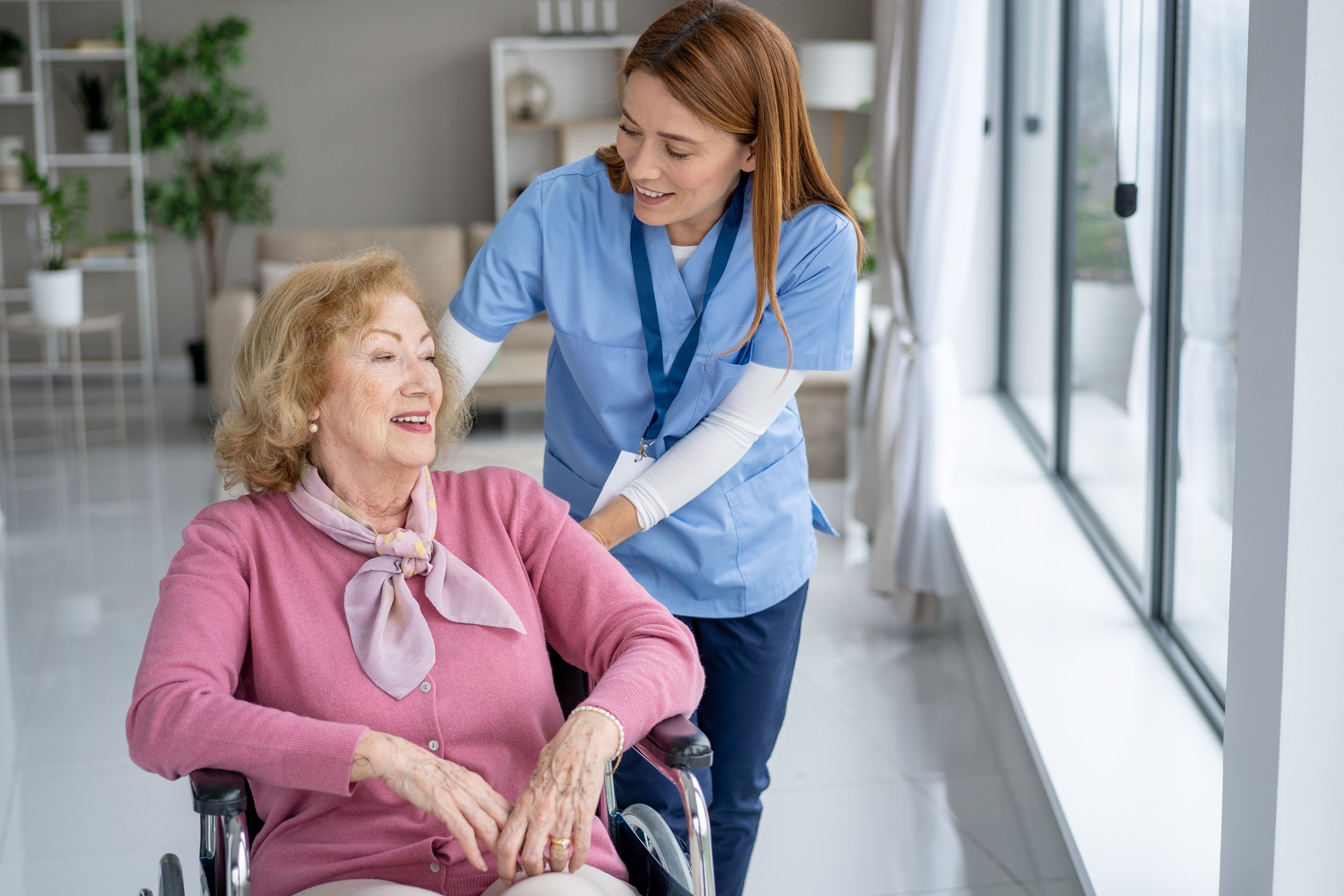 Caring nurse interacts with elderly woman in wheelchair